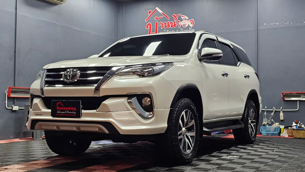 Toyota Fortuner สีขาว จอดในช่องทำงานของร้านหลังติดฟิล์มกรองแสง