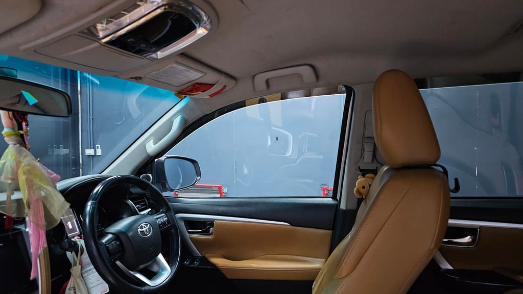 ห้องโดยสาร Toyota Fortuner เบาะหนังสีน้ำตาล คอนโซลหน้า และกระจกบานข้างที่ติดฟิล์มแล้ว